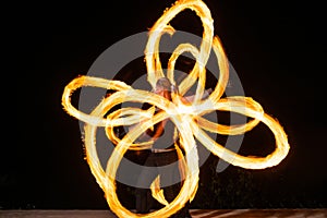 Expressive style couple of fire dancers spin burning pois creating sparkling patterns on dark outdoors, spinners