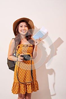 Expressive tourist woman in summer casual clothes, hat holding passport, tickets isolated on beige background. Female traveling