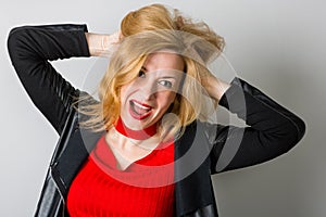 Expressive woman in a black jacket against a wall