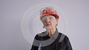 Expressive woman in safety helmet shouting into megaphone. Portrait of adult emotional construction worker. News