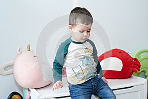 expressive young boy posing for portraits in his room surrounded by toys