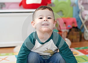 expressive young boy posing for portraits in his room surrounded by toys