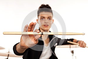 Expressive young drummer playing at the drums with drum stick