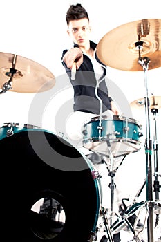 Expressive young drummer playing at the drums with drum stick