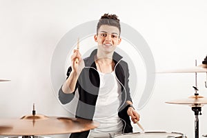 Expressive young drummer playing at the drums with drum stick