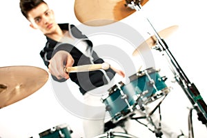 Expressive young drummer playing at the drums with drum stick