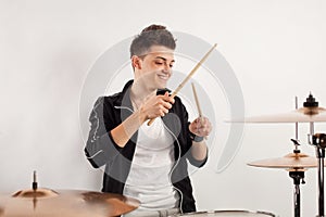 Expressive young drummer playing at the drums with drum stick