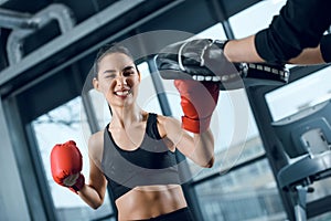expressive young female boxer exercising with trainer