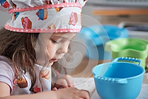 expressive young girl is playing pretend chef at home