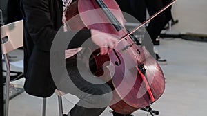 Expressive young man plays cello sitting on stage