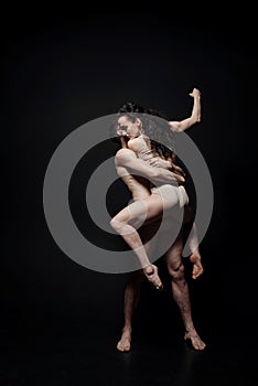 Expressive young performers dancing against black background