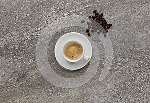 An expresso coffee, shot on a grey stone background, with a handful of coffee beans, with copy space