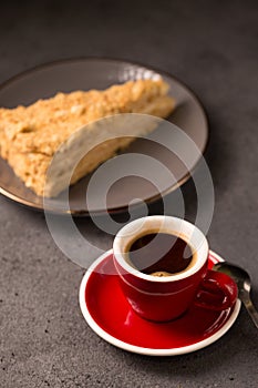 Expresso in a red coffee cup with a slice of delicious napoleon cake