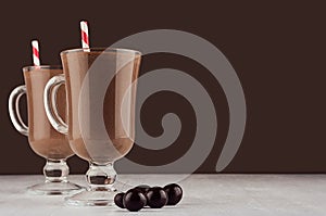 Exquisite chocolate dessert with round chocolate candies and red striped straw in dark brown interior, copy space.