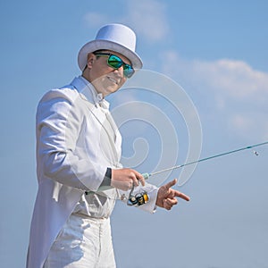 Exquisite fishing. Fisherman in white suit catch fish by spinning rod at lake