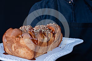 Exquisite freshly baked trenza bread decorated with caramel and walnuts on a white plate photo