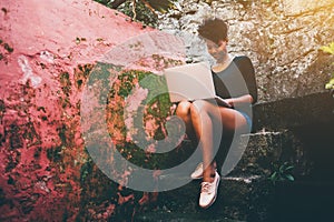 Exquisite young black woman with netbook on stony step
