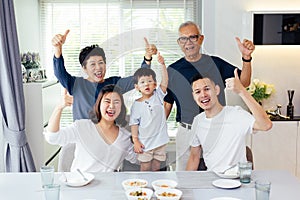 Extended Asian family of three generations having a meal together and showing thumbs up at home with happiness photo