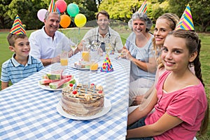 Extended family celebrating little girls birthday outside at picnic table