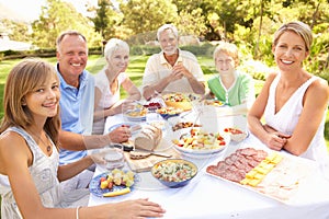 Extended Family Enjoying Meal In Garden photo