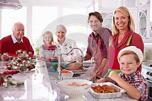 Extended Family Group Basting Christmas Turkey In Kitchen