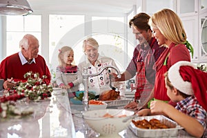 Extended Family Group Basting Christmas Turkey In Kitchen