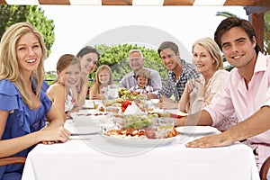 Extended Family Group Enjoying Outdoor Meal Together photo