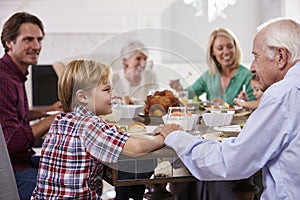 Extended Family Group Sit Around Table Eating Meal At Home