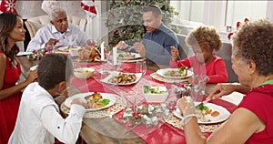 Extended family group sitting around table and enjoying Christmas meal together