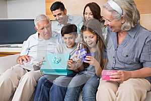 Extended family sitting on sofa with gift boxes in living room