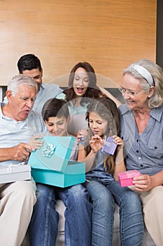 Extended family sitting on sofa with gift boxes in living room