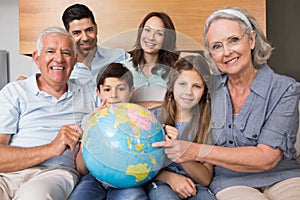 Extended family sitting on sofa with globe in living room