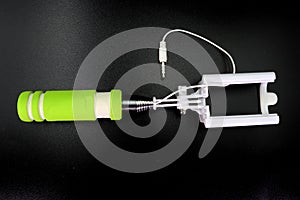 An extensible selfie stick with an adjustable clamp on the end on a white background