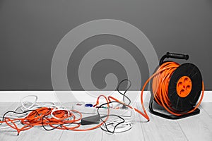 Extension cord reel plugged into power strip indoors, space for text. Electrician\'s equipment