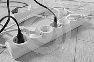 Extension cords with electrical plugs on white floor, closeup