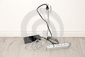 Extension cords with power plugs in socket indoors.