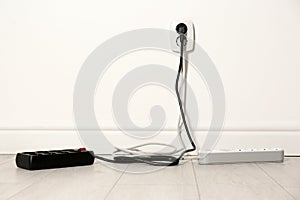 Extension cords with power plugs in socket indoors, space for text.