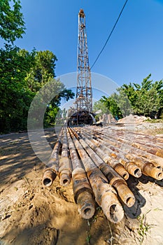 extension drilling rods in front of old water pump truck that extracts water from a hole in the ground at sunny summer