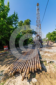 extension drilling rods in front of old water pump truck that extracts water from a hole in the ground at sunny summer