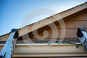 Extension step ladder against side of roof with a strand of Christmas lights