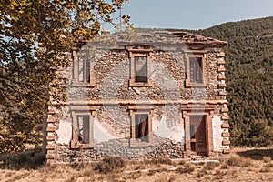 Exterior of an abandoned old brown stone house with trees with sunlight
