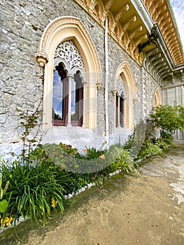 Exterior architectural details of a mansion lined with flowers and plants