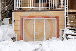 Exterior of an attached single car garage of home with snowy driveway in winter