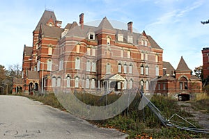 Exterior of boarded up and abandoned brick asylum hospital building with broken windows photo