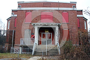 Exterior of boarded up and abandoned brick asylum hospital building with broken windows photo