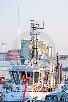 Exterior of the bridge of a white tug boat with red metal water hoses in the port