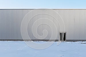 Exterior of a building of an industrial warehouse, factory or supermarket. Gray corrugated metal wall with door