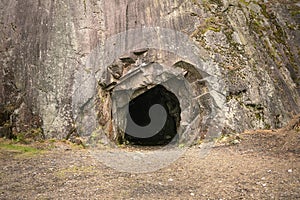 Rock wall with a dark hole, entrance to the cave in Spro, Mineral historic mine. Nesodden Norway. Nesoddtangen peninsula. photo