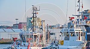 Exterior of the control bridges of two white tugboats with metallic red water hoses in