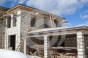 exterior of a country house under construction with scaffolding and holders for gutters water drainage system of roof. Site on